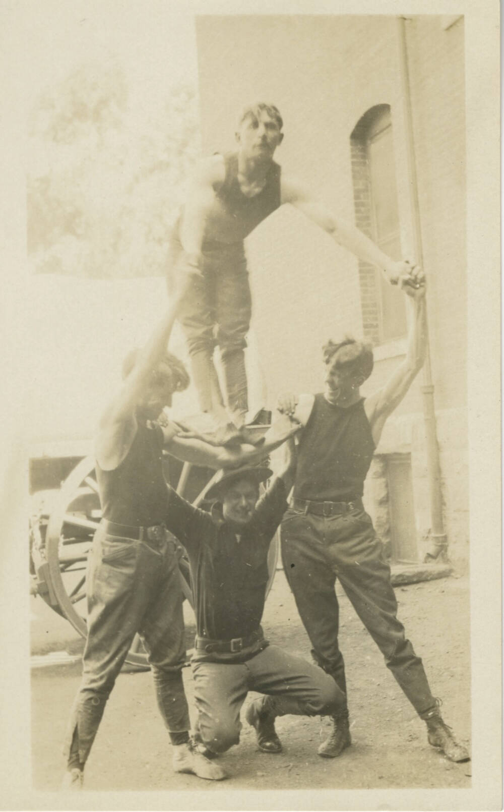 Black and white real photo postcard of four male acrobats.